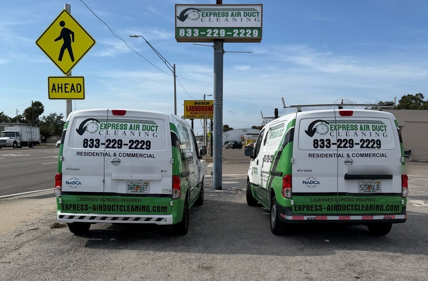 Two Express Air Duct Cleaning service vans parked in front of the company sign
